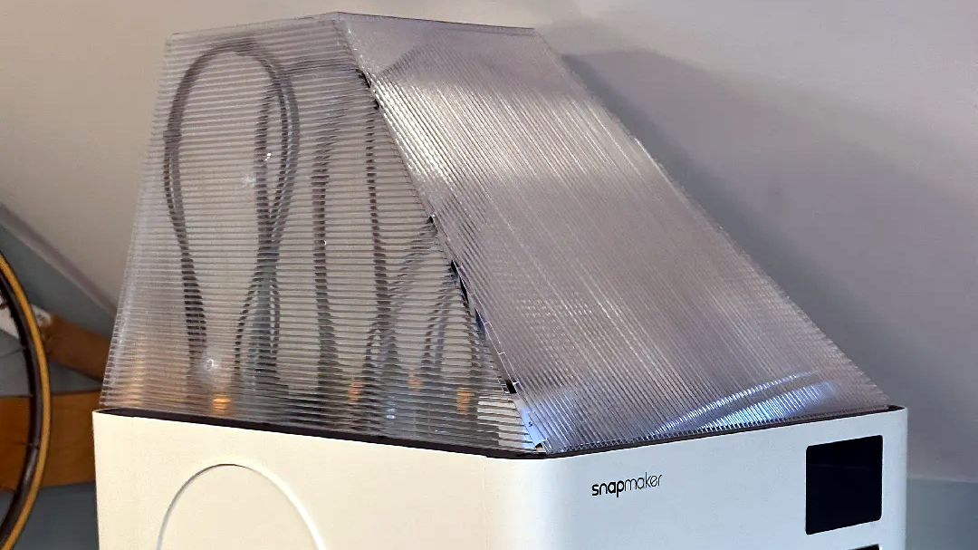 A corrugated plastic top cover taped together and fitted over the top of a desktop 3D printer to form a simple no-print enclosure
