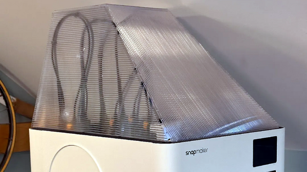 A corrugated plastic top cover taped together and fitted over the top of a desktop 3D printer to form a simple no-print enclosure