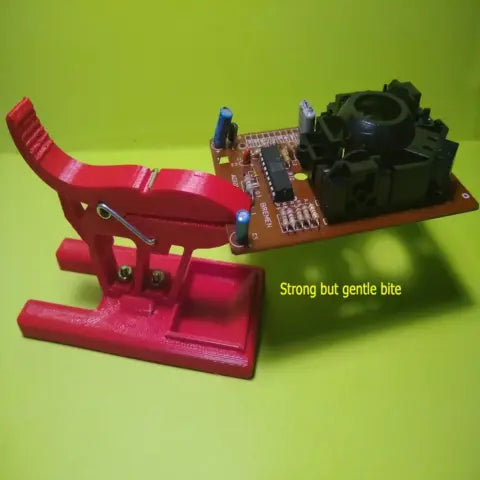 A 3D printed soldering third hand holder with an extended base gripping a small circuit board, printed in PETG